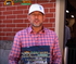 Man in plaid shirt and white cap outside.